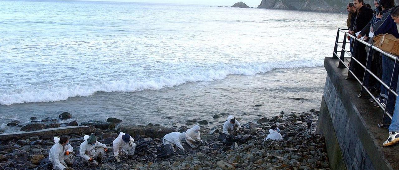 Voluntarios limpian en la playa de la Concha de Artedo, tras la «marea negra» del «Prestige», en presencia del expresidente del Gobierno José Luis Rodríguez Zapatero y otras autoridades. | Lne