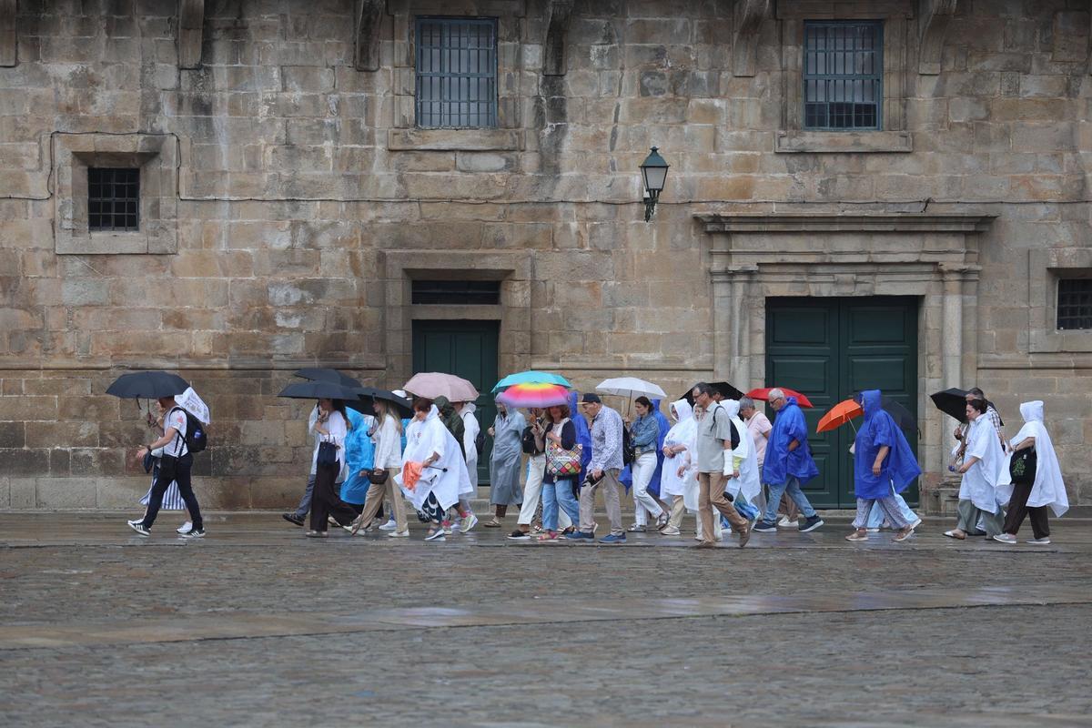 Turistas con paraguas y chuvasqueros en la Praza do Obradoiro.