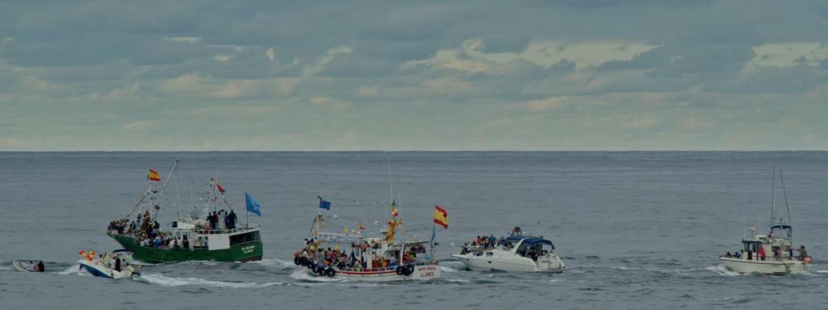 Arriba, Manuel Herrero trabaja en las redes de su barco. Sobre estas líneas, varios barcos de bajura  de la Cofradía de Santa Ana de Llanes; a la derecha, cartel del documental. | Á. G.