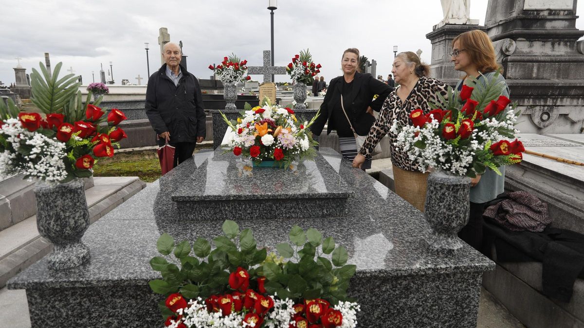 Un grupo de familiares coloca flores en una tumba.
