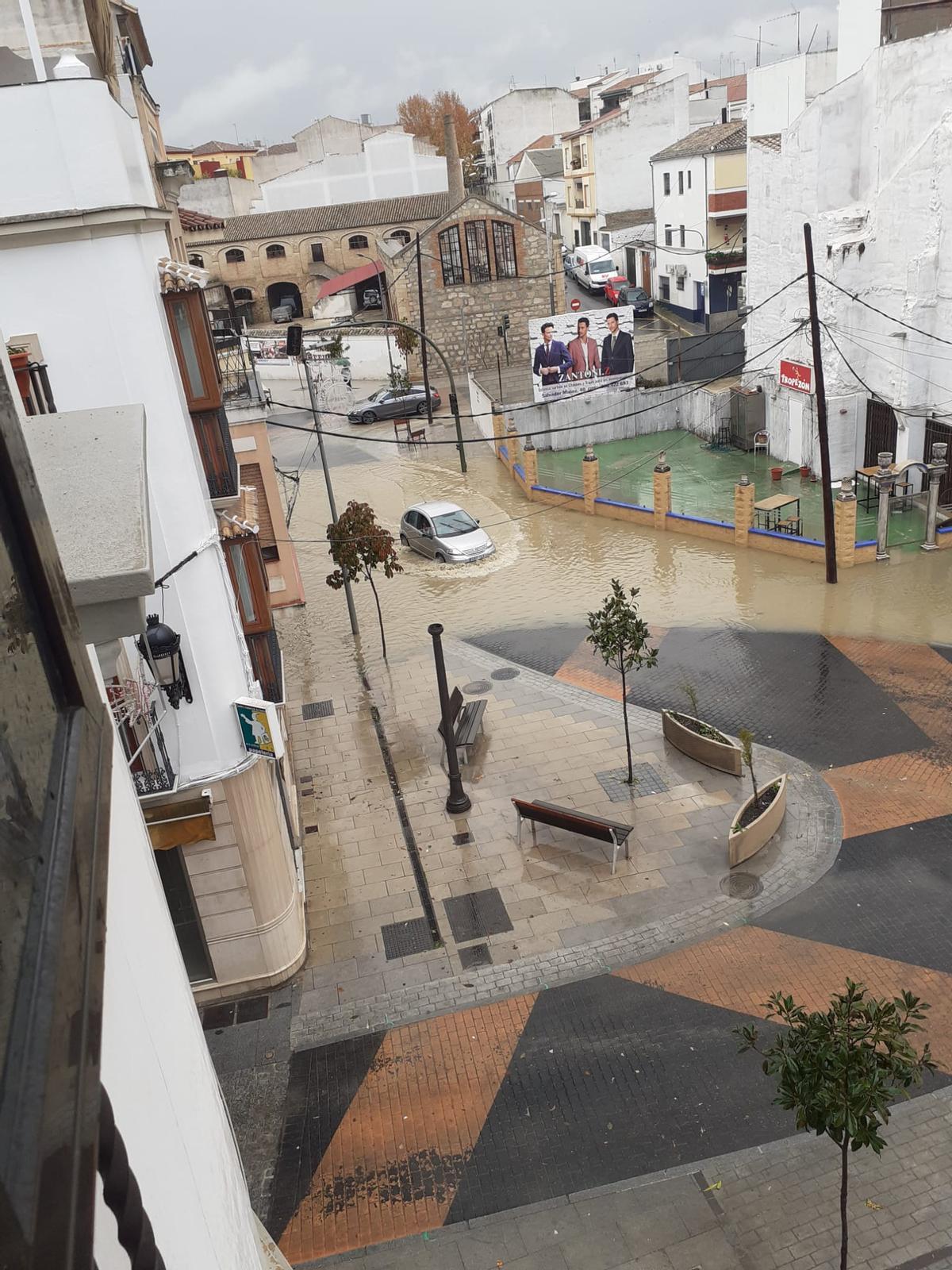 Un coche atraviesa una zona inundada en Baena.