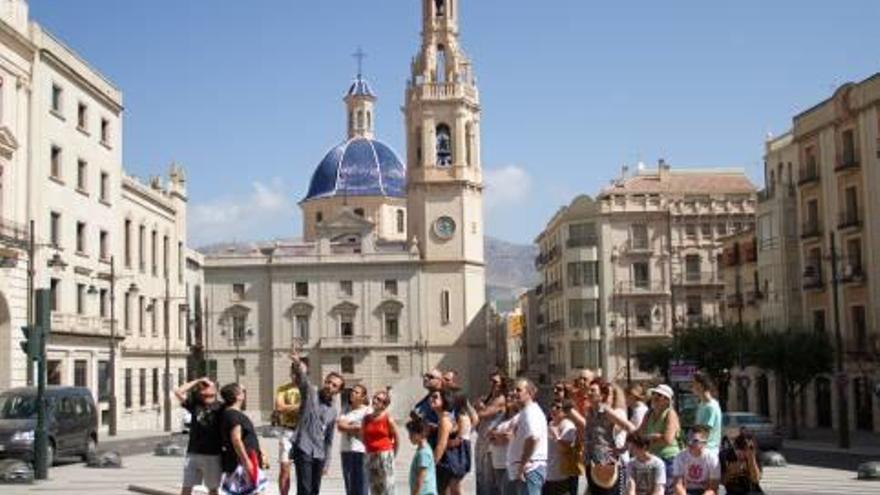 Los asistentes junto al guía en la plaza de España de Alcoy, desde donde partía la ruta, y una de las calles con edificios modernistas que se visitaron.