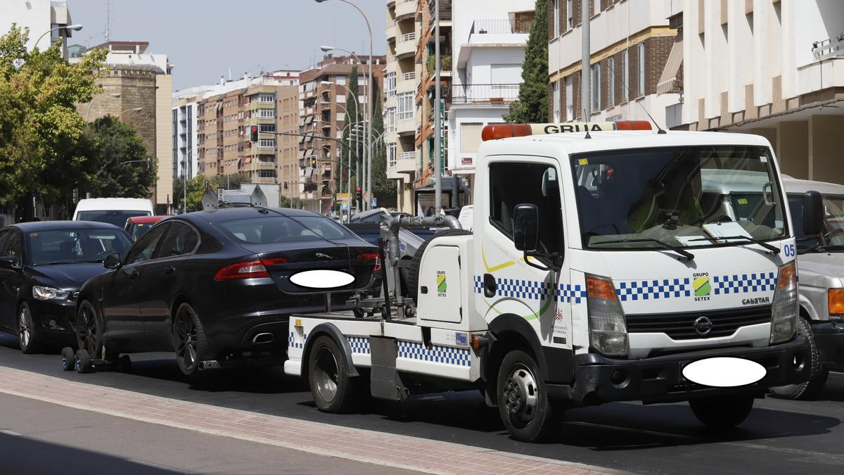 Una grúa municipal retira un coche en una de las avenida más transitadas de Córdoba.