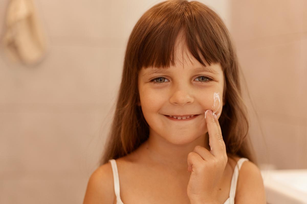 Una niña aplicándose crema hidratante, que solo es recomendable en pieles secas