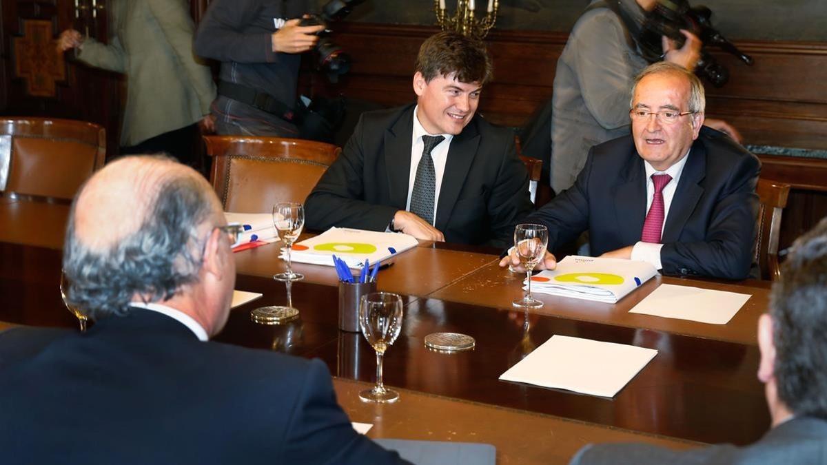 El presidente de la Plataforma contra la Morosidad, Antoni Cañete, en el centro, junto a Josep González, de PIMEC, en una reunión con el minitro Montoro (de espaldas).