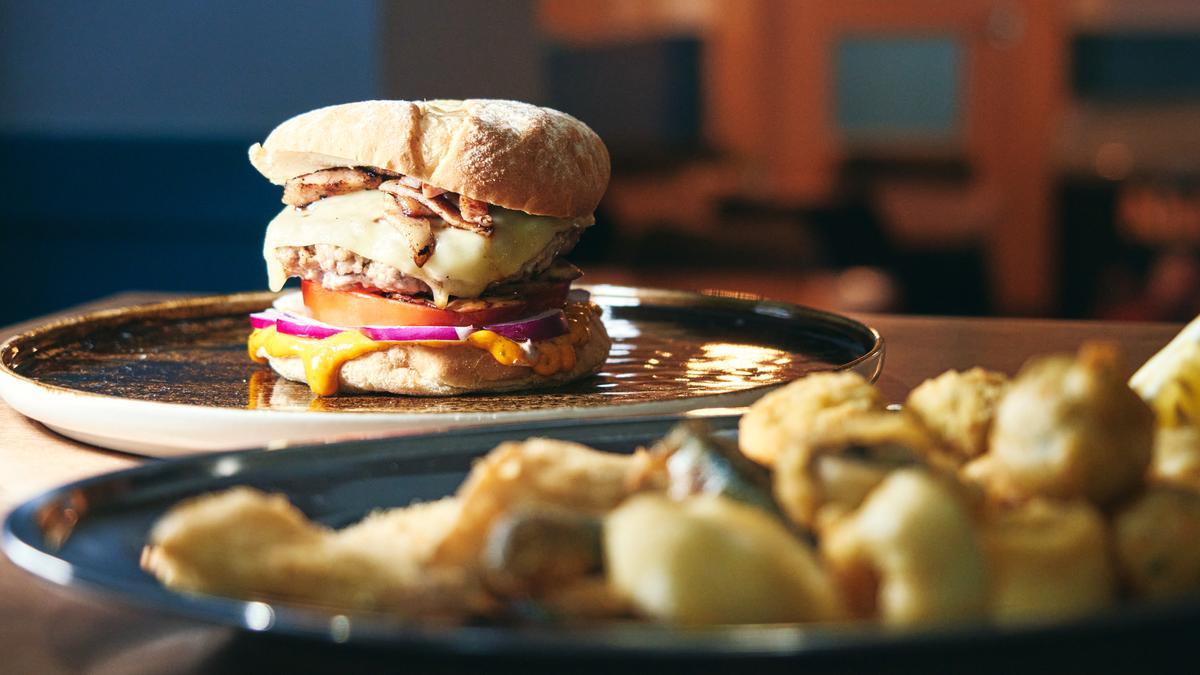 Una de las hamburguesas de autor de La Pacheca y un plato de 'pescaíto' andaluz.