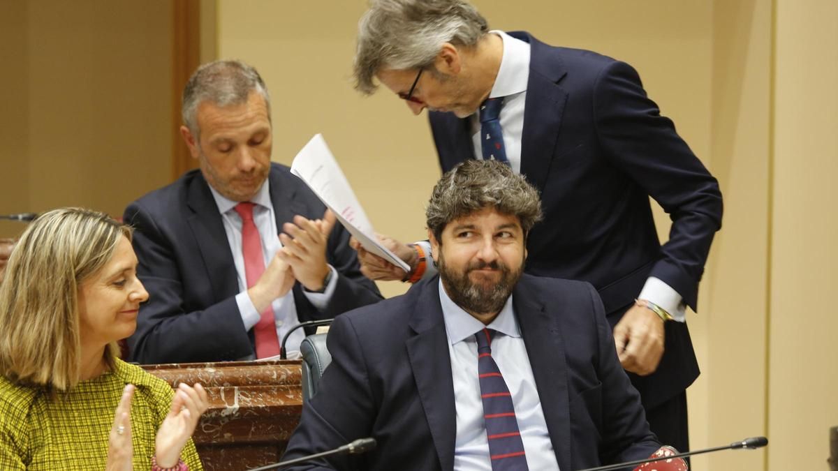 El consejero de Hacienda, Luis Alberto Marín, vuelve a su escaño entre los aplausos de Joaquín Segado (atrás), Conchita Ruiz y Fernando López Miras.