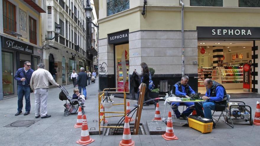 Operarios de una empresa de telecomunicaciones instalan cable en el centro de la ciudad.