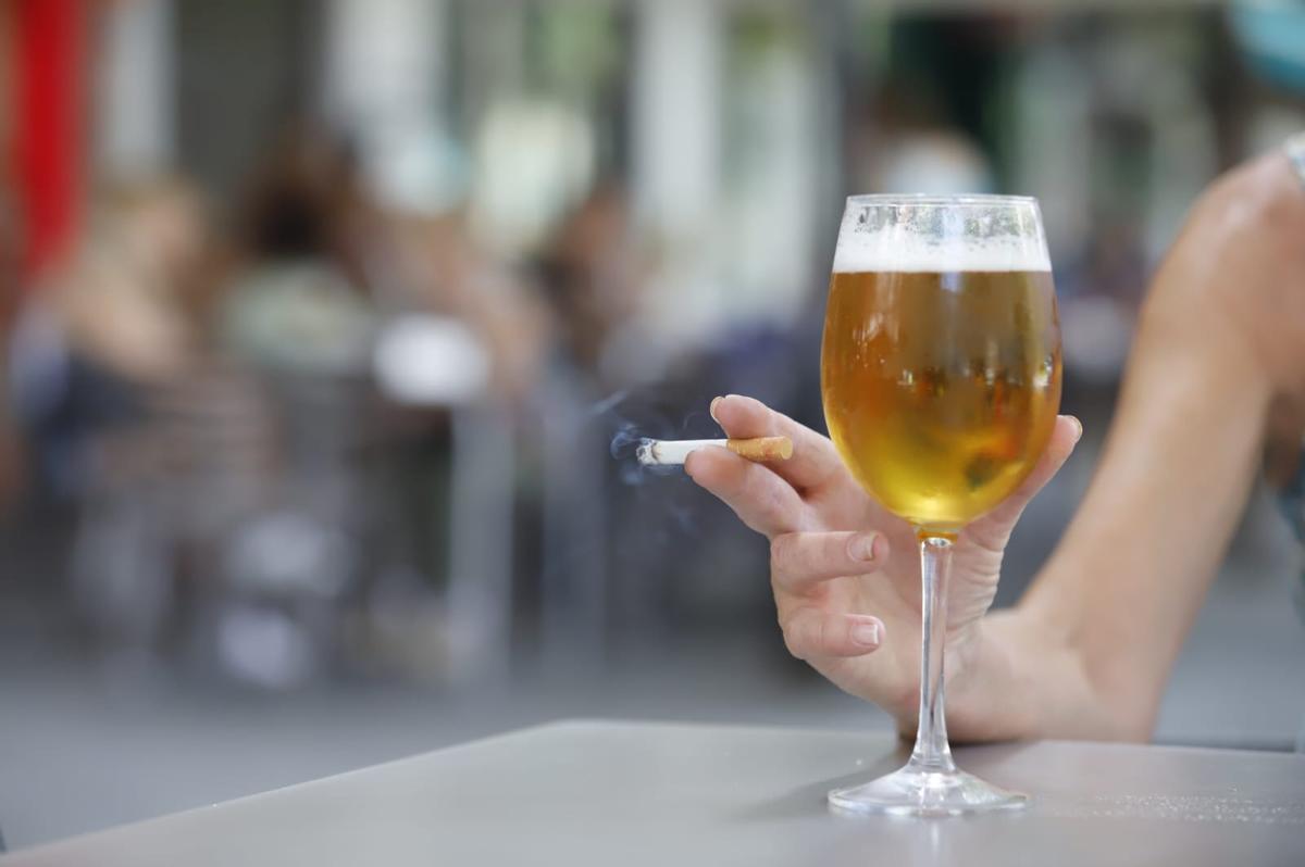 Una fumadora, con una cerveza y un cigarro en la mano.