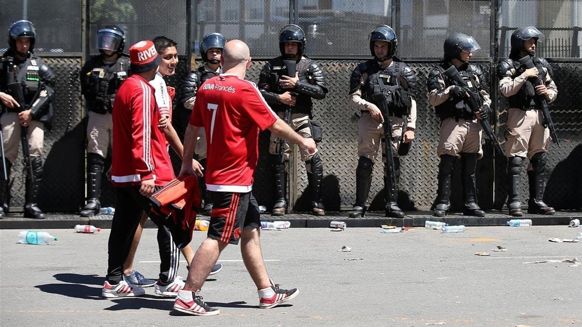 Aficionados del River pasan por delante de las fuerzas policiale s tras ñla suspensión del partido el pasado sábado.