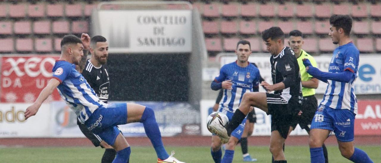 El árbitro, Mallo Fernández, observa una disputa entre Prendes y un jugador del Compostela en el partido del pasado sábado. | Área 11