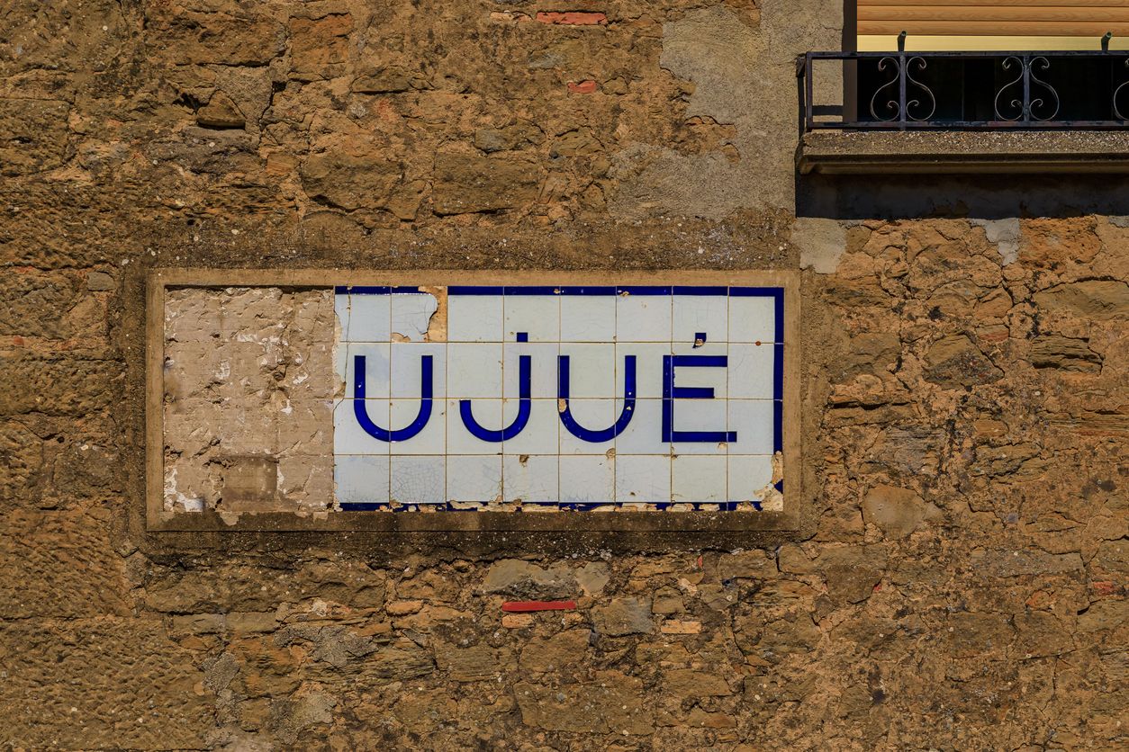 Antiguo letrero de azulejos con el nombre del pueblo en el pueblo medieval de Ujue, España - Foto de stock