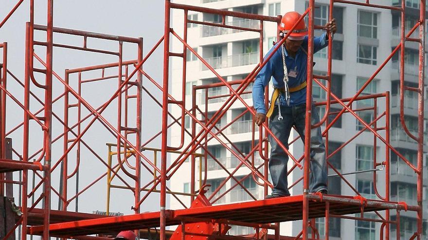 Dos operarios trabajan en una obra subidos a un andamio.