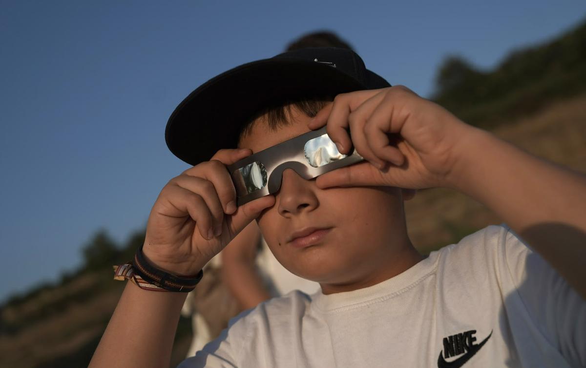 Un niño observa el eclipse con las gafas de protección. Un niño observa el eclipse con las gafas de protección.
