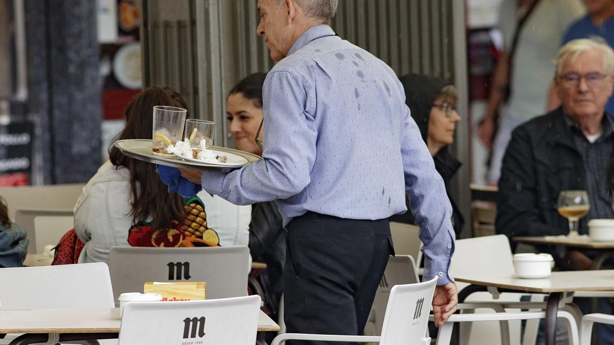 Archivo - Un camarero porta una bandeja en una terraza de un bar de Madrid