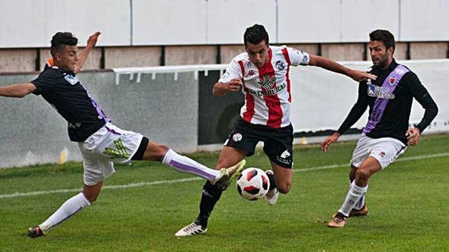 Dani Hernández conduce el balón entre dos rivales del Numancia B.