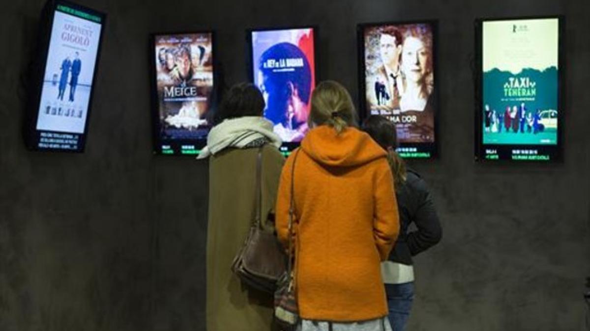 Tres jóvenes revisan la oferta del cine de reestrenos Texas.