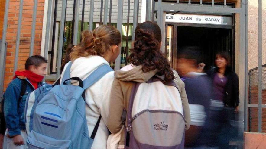 Alumnos con mochilas a la entrada de un colegio.