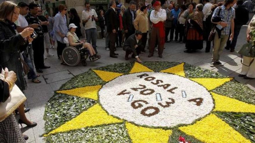 El alcalde, agachado, ante la alfombra floral en honor a Rosalía, en la Praza de Almeida.  // Fotos de José Lores