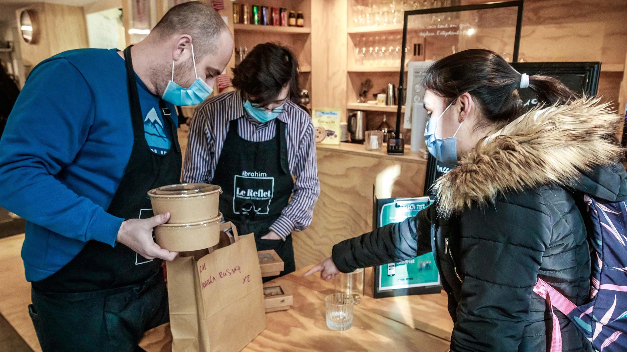 Una estudiante universitaria recoge un menú solidario del restaurante parisino Le Reflet.