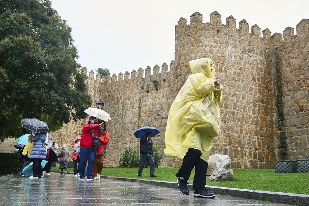 Varias personas se protegen de la lluvia este jueves en Ávila. EFE/Raúl Sanchidrián