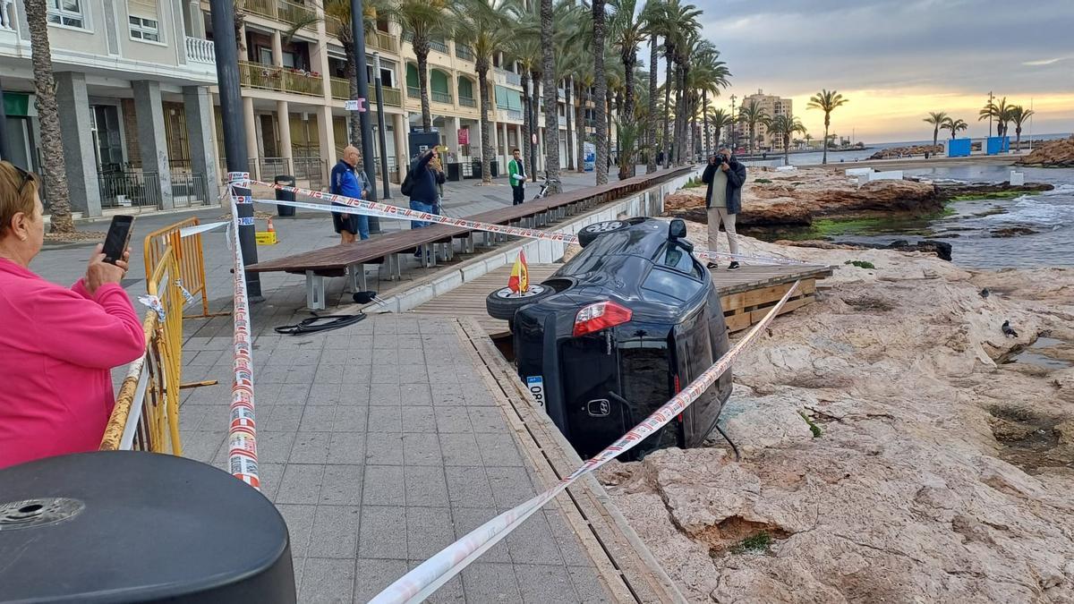 Los bomberos rescatan a una conductora atrapada tras sufrir un accidente en el paseo marítimo de Torrevieja y precipitarse el vehículo sobre las rocas