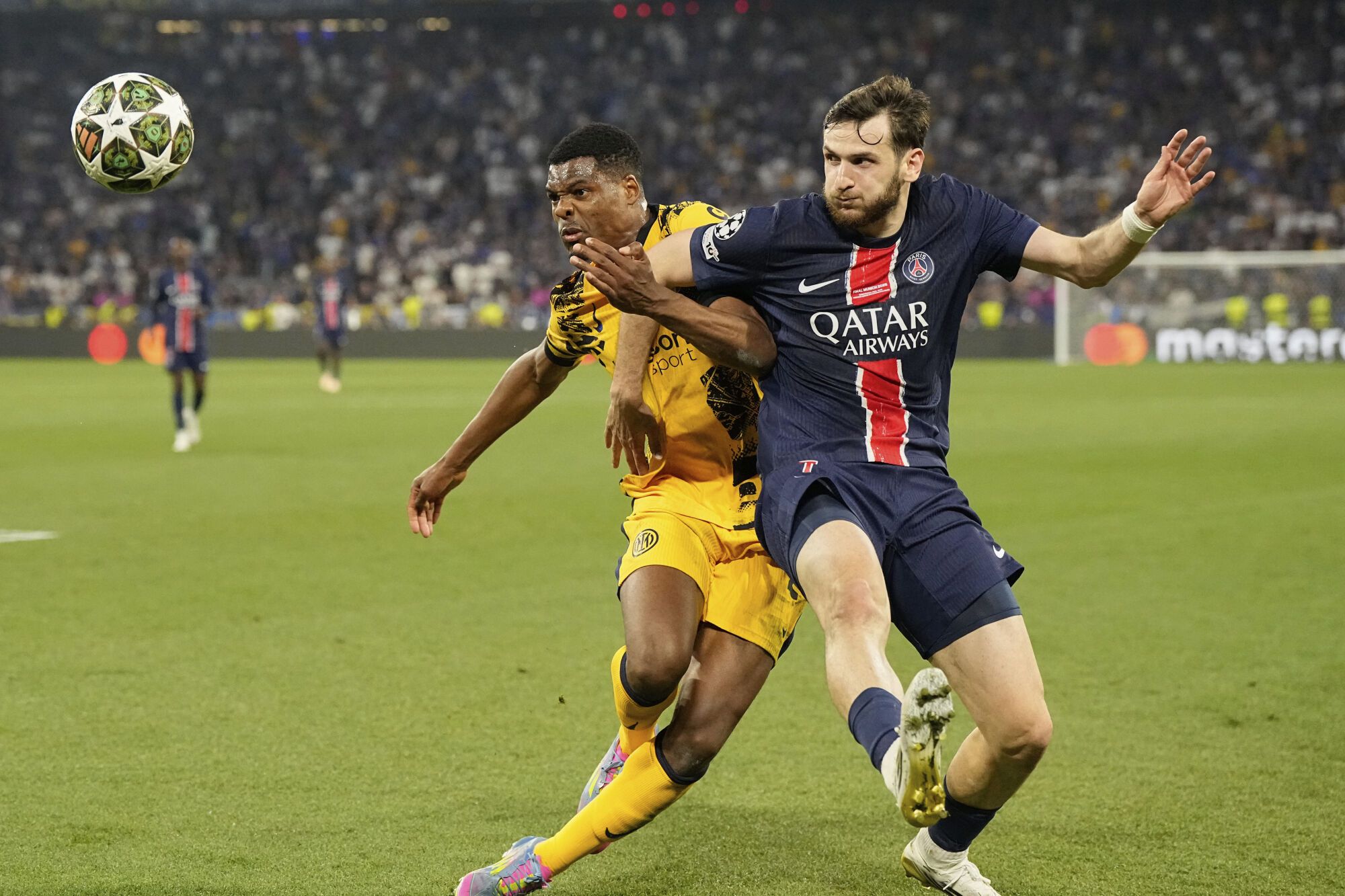 PSG's Khvicha Kvaratskhelia, right, fights for the ball with Inter Milan's Denzel Dumfries during the Champions League final soccer match between Paris Saint-Germain and Inter Milan at the Allianz Arena in Munich, Germany, Saturday, May 31, 2025. (AP Photo/Martin Meissner)