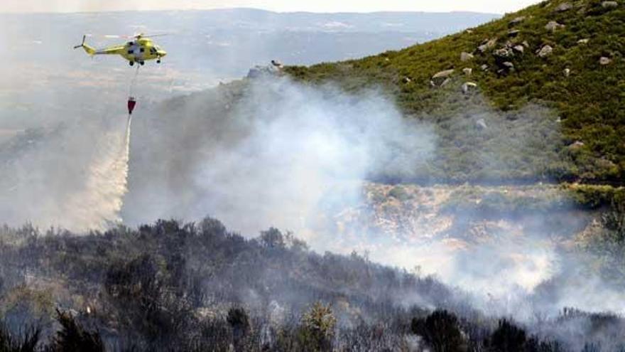 Un helicóptero trabaja en las labores de extinción del incendio forestal declarado ayer a última hora de la tarde en el municipio de Oímbra (Ourense) que permanece activo y ya ha calcinado más de 200 hectáreas.