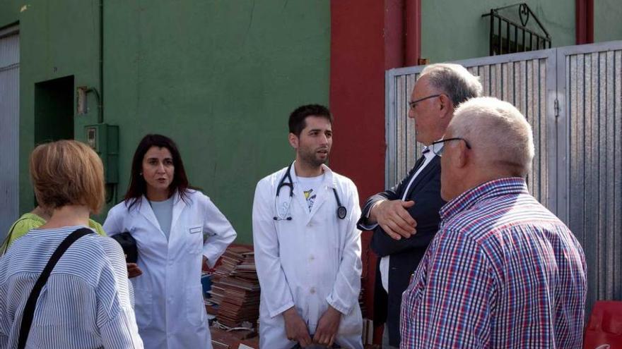 El concejal José Manuel Álvarez, de espaldas, y el secretario municipal, Miguel Ángel de Diego, charlan con el médico en el exterior de la vivienda en la que reside la familia.