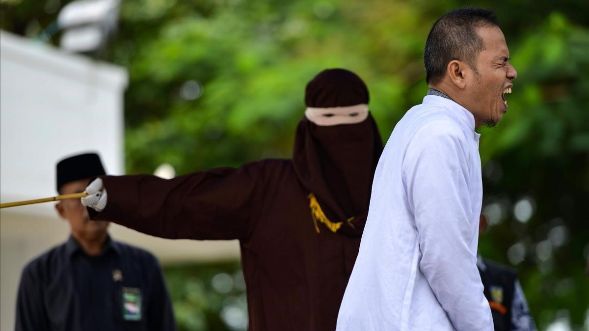 Mukhlis bin Muhammad se duele al encajar un latigazo de la policía de la sharia en la ciudad indonesia de Banda Aceh tras ser sorprendido cometiendo adulterio. Mukhlis bin Muhammad se duele al encajar un latigazo de la policía de la sharia en la ciudad indonesia de Banda Aceh tras ser sorprendido cometiendo adulterio.
