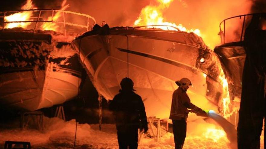 Varios bomberos arrojan espuma sobre las embarcaciones incendiadas, ayer en Eivissa.