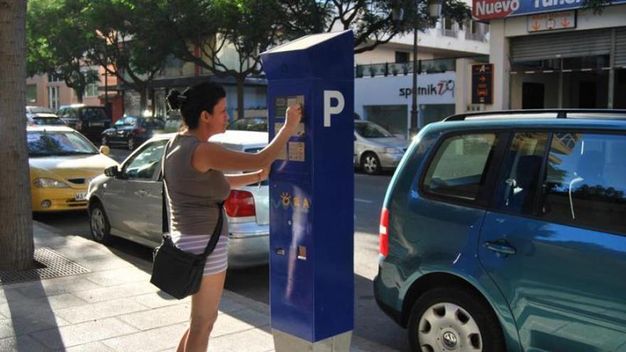 Una usuaria paga el estacionamiento de su vehículo a través de una máquina expendedora