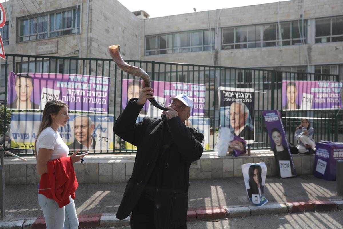  Un hombre toca un shofar junto a carteles electorales durante las elecciones generales israelíes en Jerusalén, Israel.
