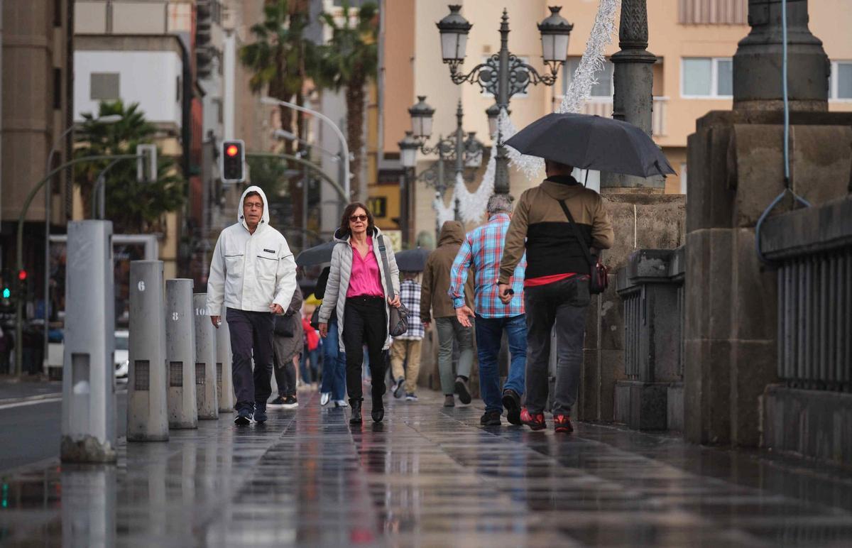 Vecinos se protegen de la lluvia en Santa Cruz de Tenerife.