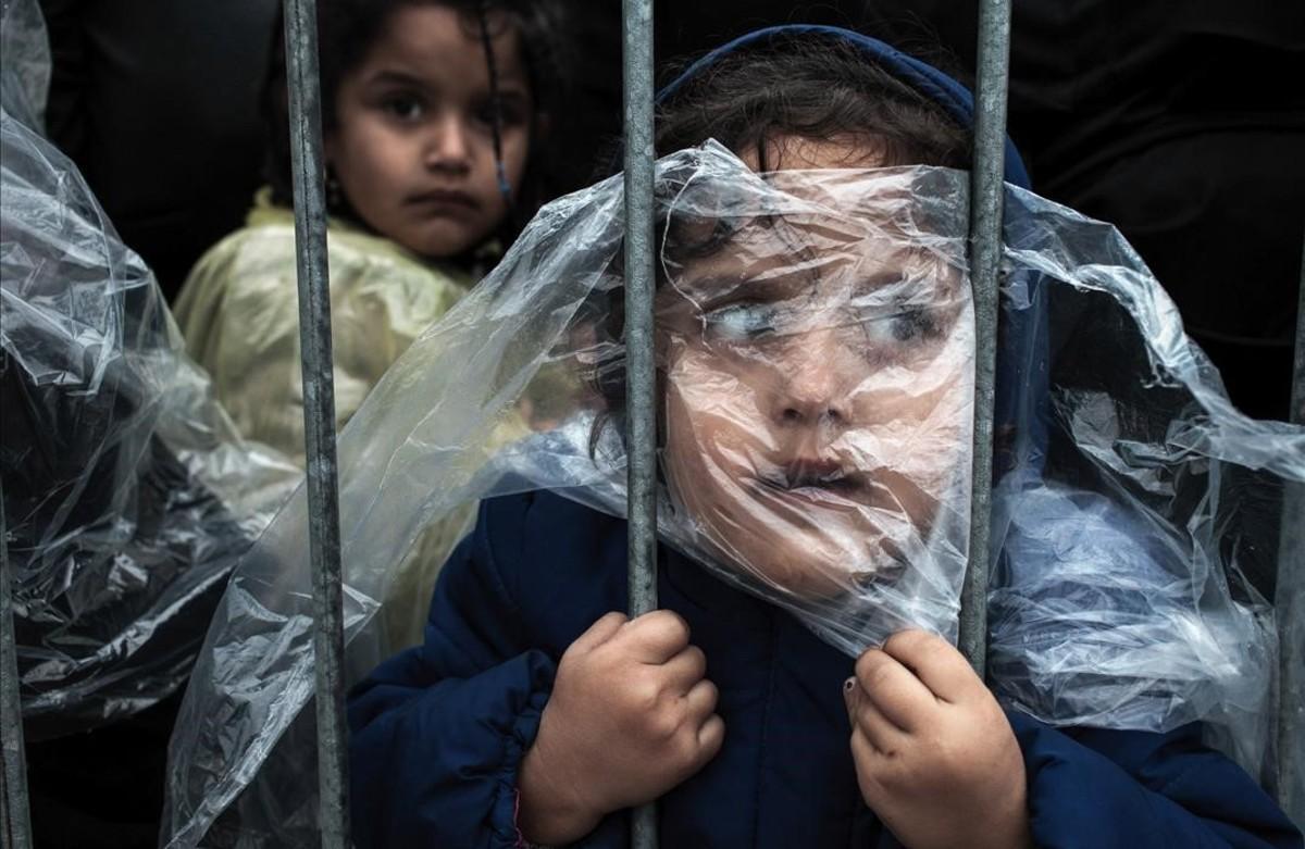 Niños refugiados tapados con plásticos para refugiarse de la llulvia esperan para registrarse en Serbia. Es una de las imágenes premiadas en el World Press Photo.  
