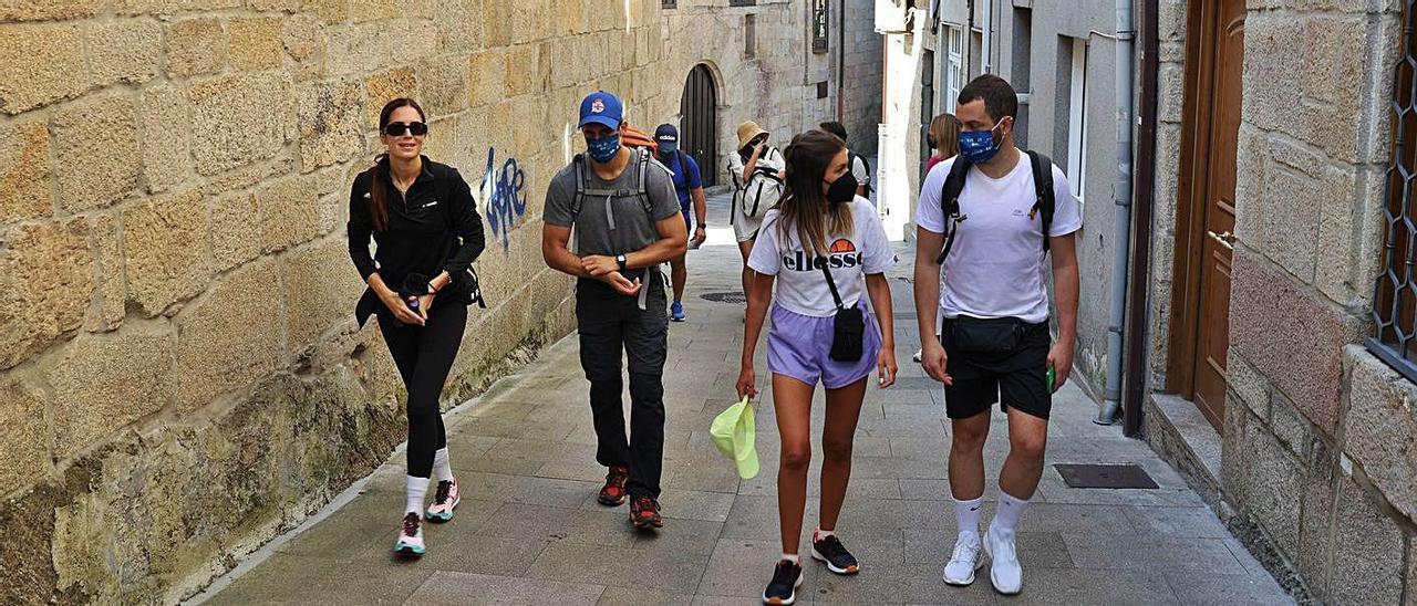 Unos peregrinos caminan por una calle del casco antiguo de Redondela.