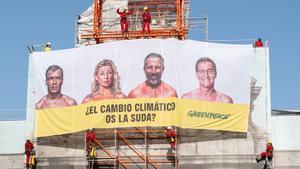La Puerta de Alcalá amanece tapada por una pancarta con la cara de los candidatos y la frase: “¿El cambio climático os la suda?”