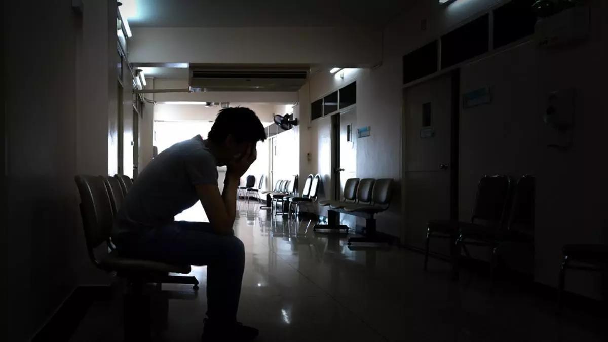 Una persona agobiada en el pasillo de un centro hospitalario