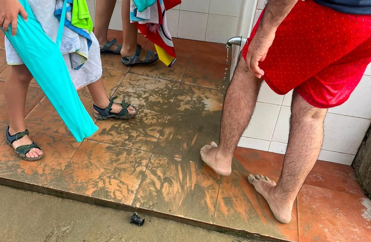Usuarios de la playa de Aguilar, en Muros de Nalón, en la zona de duchas con el caño sin agua.