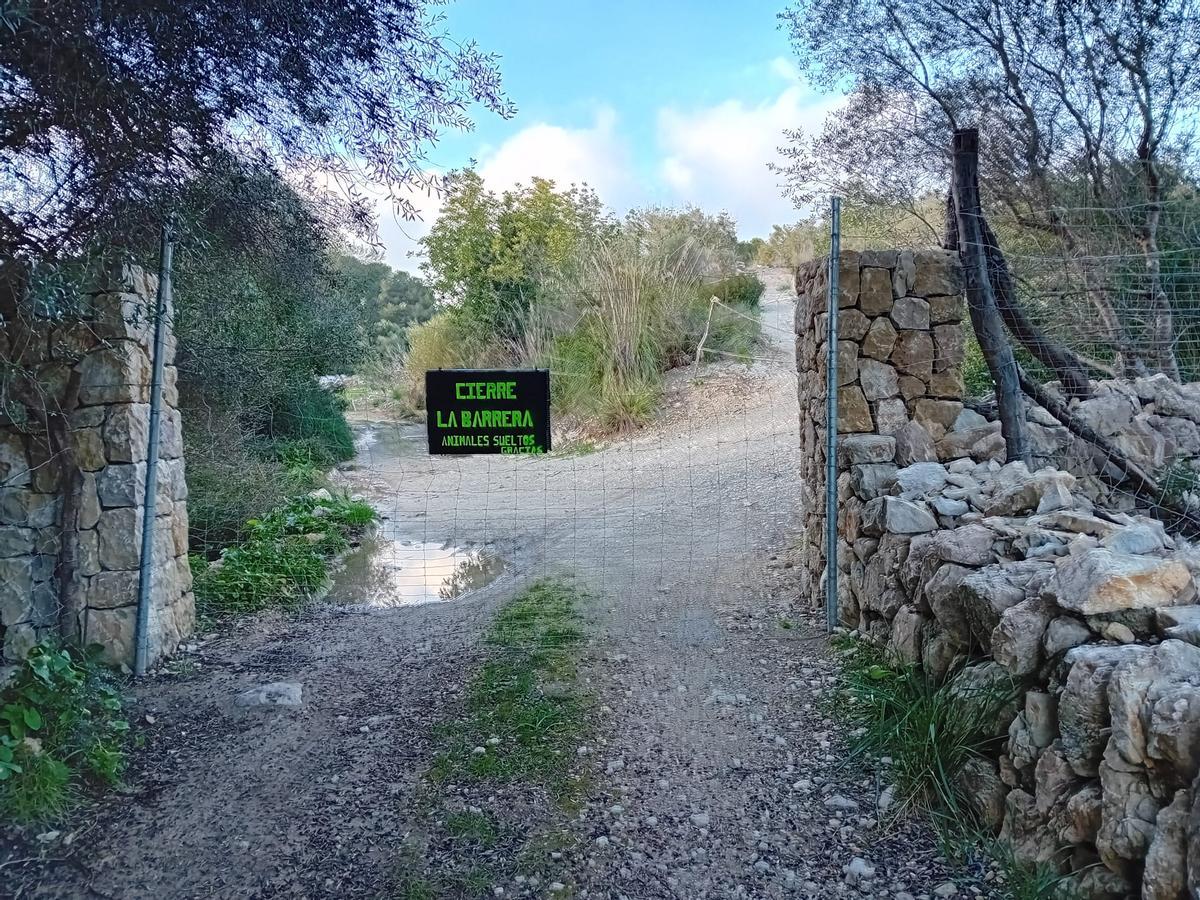 Barrera metálica que obstaculiza el acceso por el camino público.