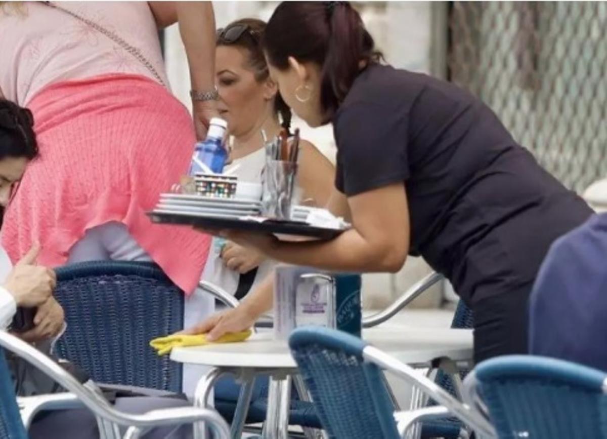 Una camarera atiende a en la terraza de un establecimiento hostelero.