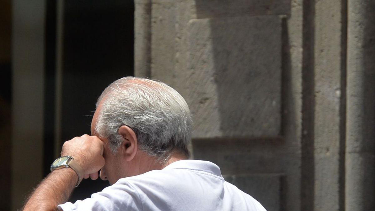 Un hombre camina con la mascarilla colgada en el codo. | | J