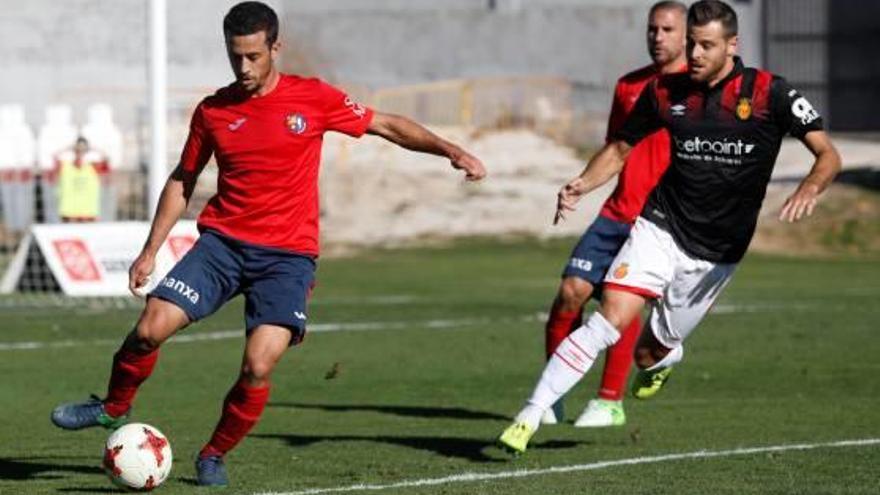 Micaló refusa una pilota davant la pressió d&#039;un jugador del Mallorca al Municipal olotí.