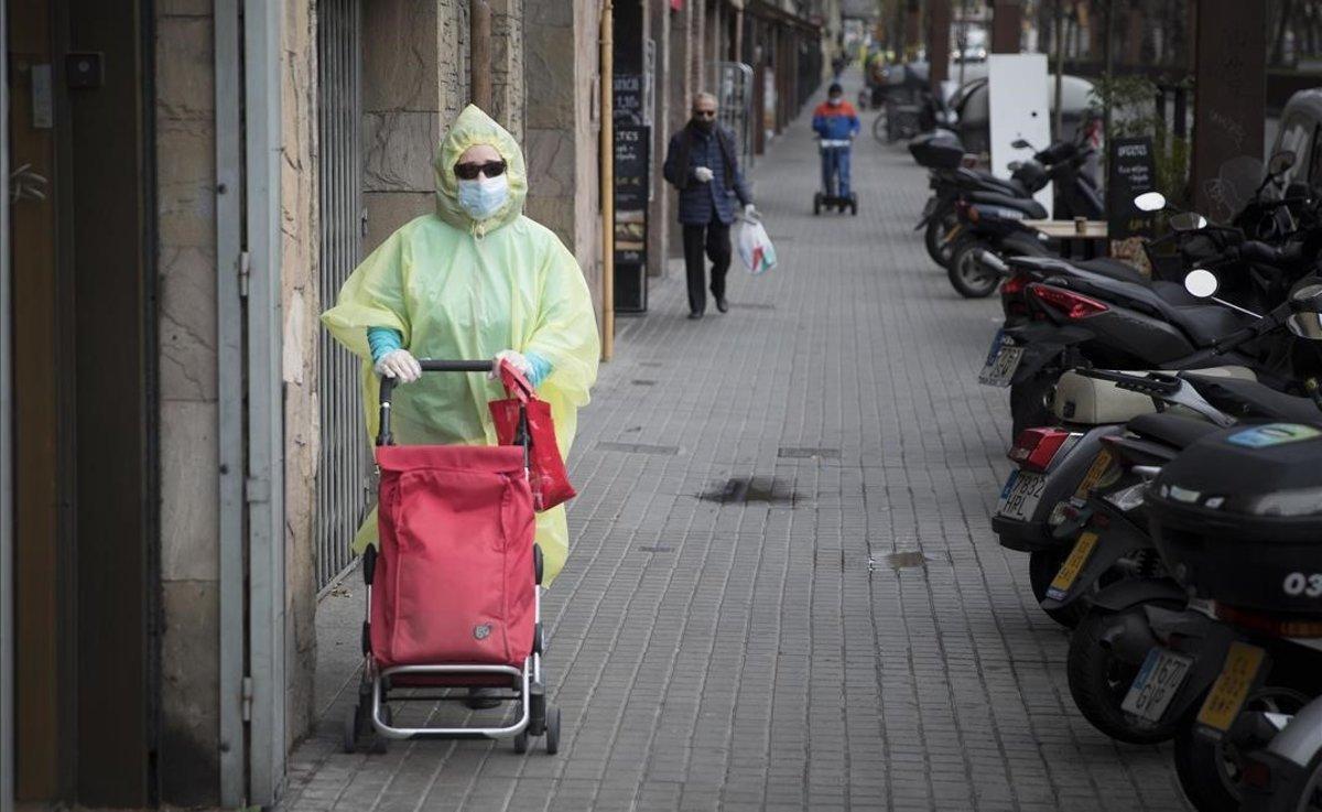 Una mujer sale a comprar por Barcelona totalmente protegida para prevenir el contagio por coronavirus.