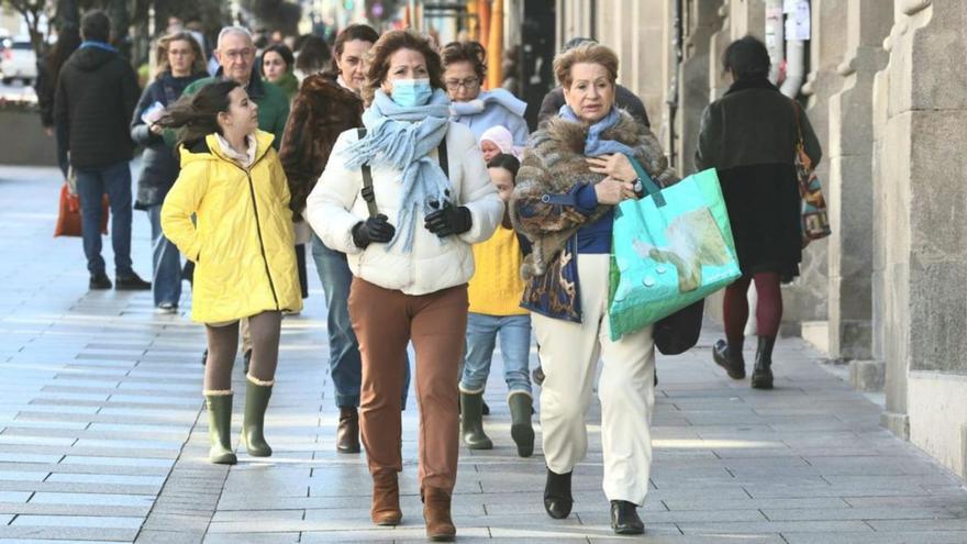 Varias personas caminan abrigadas por la viguesa calle Urzáiz. |   // MARTA G. BREA