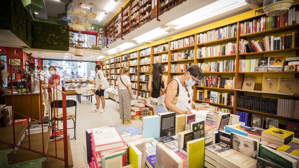 Personas en una librería zaragozana consultando algunos libros y nuevas lecturas en papel.