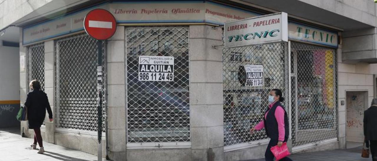 Una mujer pasa delante de un local cerrado en Vigo. |   // R. GROBAS
