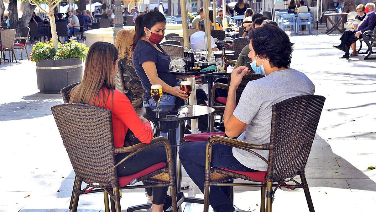 Una camarera atiende a una pareja de clientes en una de las terrazas que están ubicadas en la ciudad de Elche. | MATÍAS SEGARRA