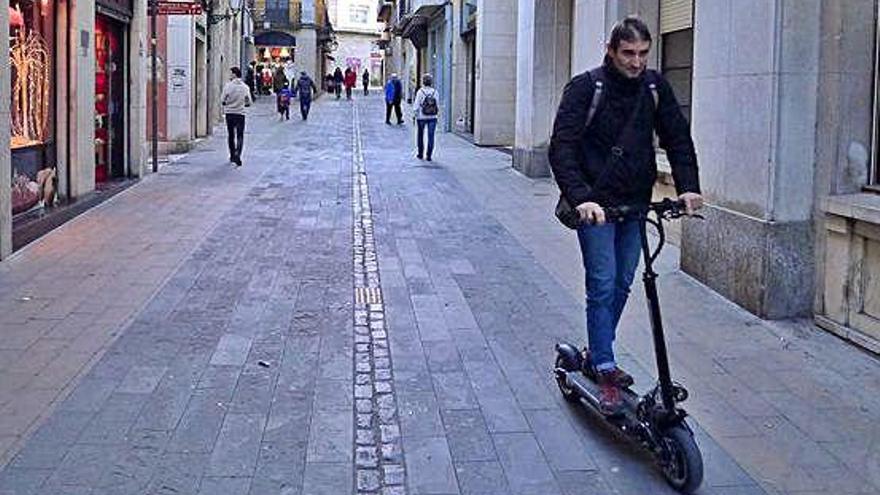 Una persona circulant amb un patinet a la plaça de l&#039;Ajuntament de Figueres.