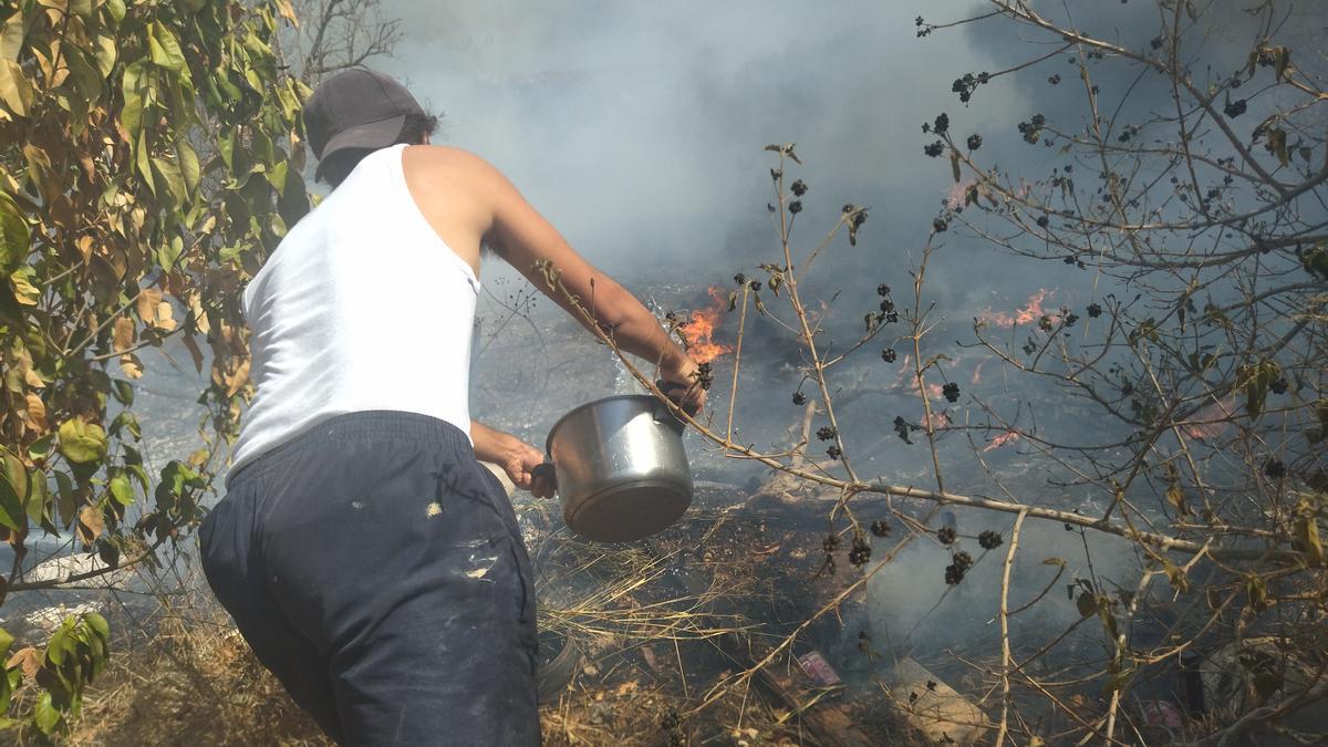 Un veí combat el foc llançant-hi aigua amb una cassola